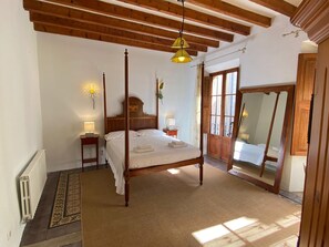 A four-poster bed with a wooden headboard, a bedside table with a lamp, and a large mirror on the wall.