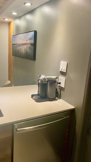 A hotel room with a kitchenette, a painting on the wall, and a power outlet. - Zen2 Stylish Modern/Rustic Apartment in the Heart of Nature (Saint-Zénon)