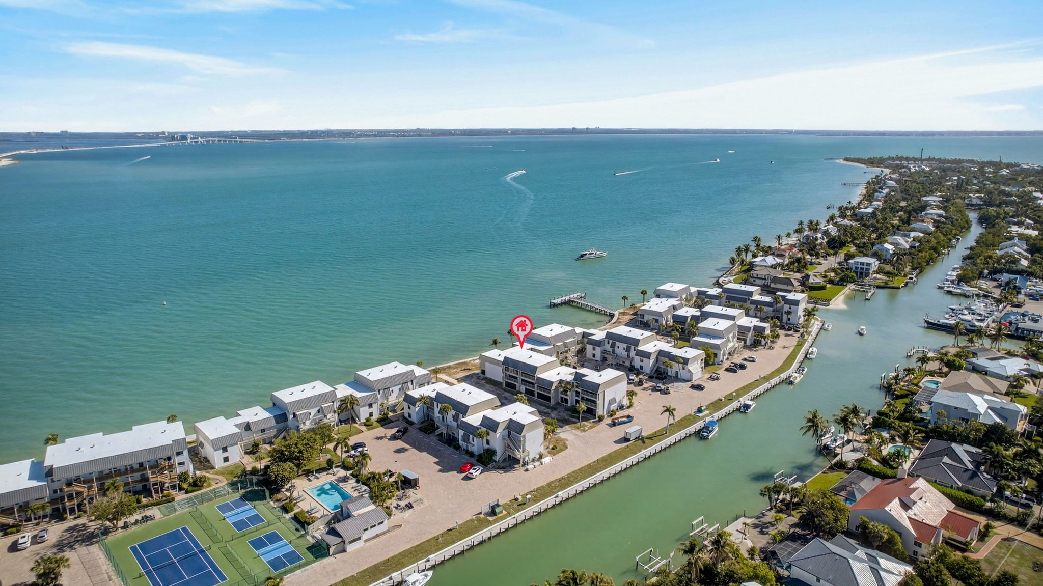 Ein Küstenresort mit mehrstöckigen Gebäuden, einer Marina und einem Tennisplatz.