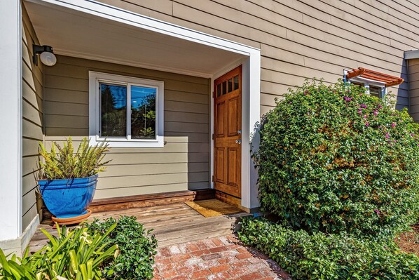 Enter a charming home with a welcoming entrance, complete with a door, window, and lush greenery.