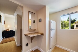 Relax in a serene space with a shelf, refrigerator, and large window overlooking lush greenery.