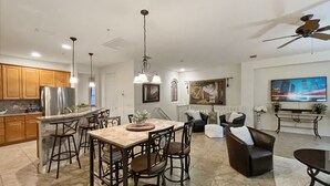 Uma sala de estar ampla com uma mesa de jantar, cadeiras, sofá e televisão.