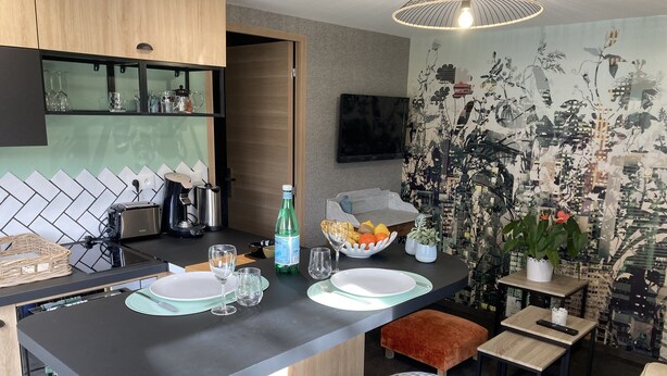 A modern kitchen with a black countertop, a wooden cabinet, and a decorative wall mural. - Le Clos des Feugrais*** - Quiet outbuilding (Saint-Aubin-lès-Elbeuf)