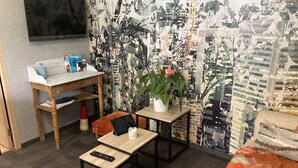 A cozy living area with a sofa, a coffee table, and a small wooden table with a remote control. A TV is mounted on the wall, and there's a plant on a side table. - Le Clos des Feugrais*** - Quiet outbuilding (Saint-Aubin-lès-Elbeuf)