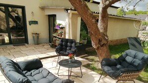 An outdoor seating area with two cushioned chairs and a small table, surrounded by potted plants and a tree. - Le Clos des Feugrais*** - Quiet outbuilding (Saint-Aubin-lès-Elbeuf)