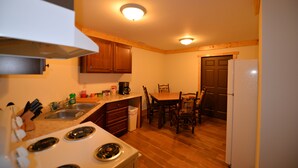 A compact kitchen with wooden cabinets, a stove, a sink, and a dining area with chairs and a table. - Spectacular bluff views facing west.  Magnificent sunsets! (Lookout Mountain)