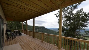 A wooden deck with a railing, outdoor furniture, and a scenic view of a forested valley. - Spectacular bluff views facing west.  Magnificent sunsets! (Lookout Mountain)