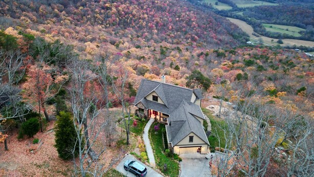 A house with a steep roof, surrounded by a forested area with autumn foliage. - Spectacular bluff views facing west.  Magnificent sunsets! (Lookout Mountain)