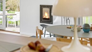 Un intérieur moderne avec une cheminée, un coin repas et une vue sur l’extérieur.
