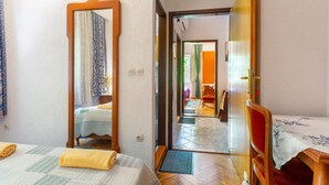 Une chambre d’hôtel avec un lit, un grand miroir, une porte en bois et une vue sur le couloir.