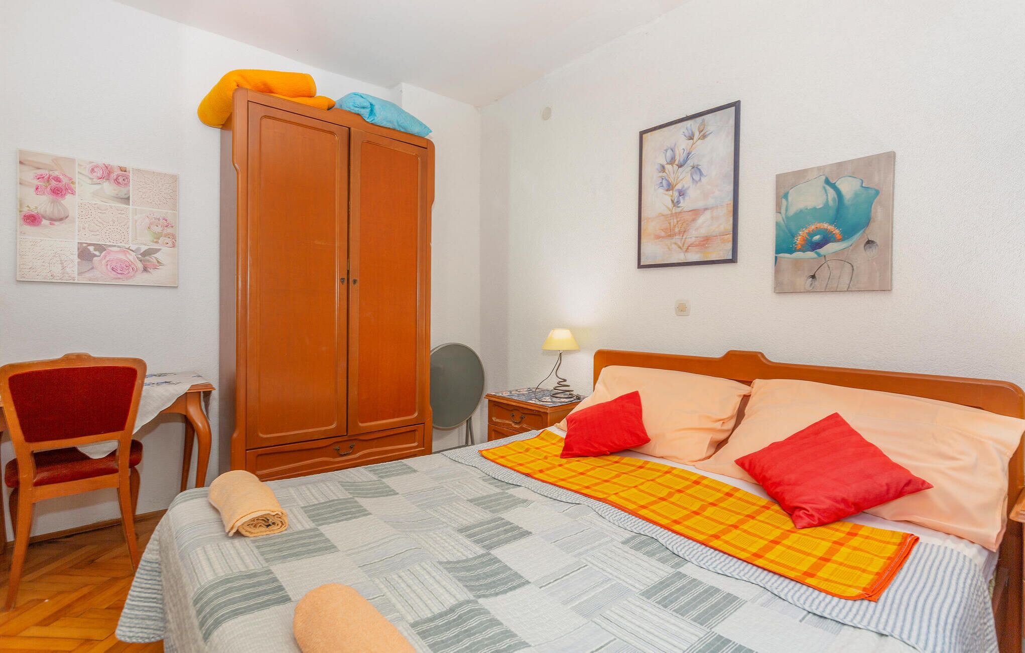 A bedroom with a bed, a wardrobe, a desk, and two chairs.