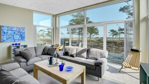 A modern living room with a large sectional sofa, a coffee table, and a view of the outdoors through large windows. - Stunning home in Hals with sauna (Hals)