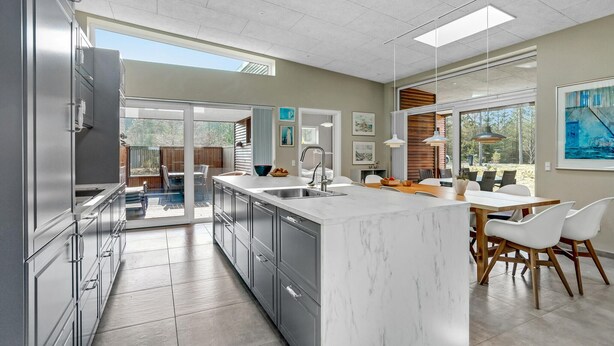 A modern kitchen with a large island, stainless steel appliances, and a dining area with white chairs. - Stunning home in Hals with sauna (Hals)
