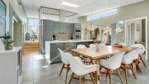 A modern kitchen with grey cabinets, a central island, and white chairs around a wooden table. - Stunning home in Hals with sauna (Hals)