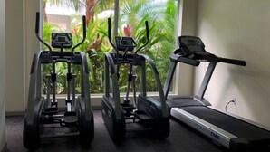 Ein Raum mit drei Trainingsgeräten: zwei Crosstrainern und einem Laufband.