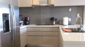 Eine moderne Küche mit einem Edelstahl-Kühlschrank, einem Einbauofen, einer Kaffeemaschine und einem Spülbecken.