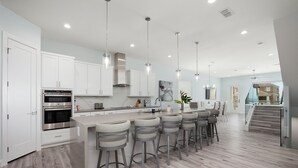 A modern kitchen with white cabinets, stainless steel appliances, and a central island with bar stools.