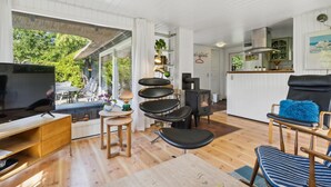 Uma sala de estar moderna com televisão, mobiliário de madeira, lareira e vista para o exterior.
