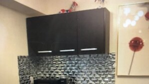 Eine Küche mit schwarzen Schränken, einer Mikrowelle und einer gefliesten Spritzschutzwand.