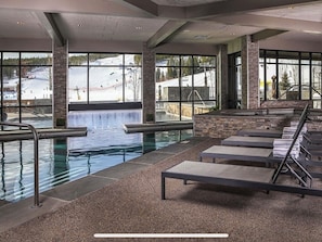 An indoor swimming pool with clear views of a snowy landscape through large windows.