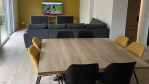 A modern living room with a large wooden dining table, grey sofas, and yellow chairs. - Charming house on the Opal Coast, 5 minutes from the beach by car (Wimille)