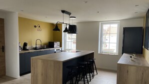 A modern kitchen with a central island, bar stools, a coffee machine, and a microwave. - Charming house on the Opal Coast, 5 minutes from the beach by car (Wimille)