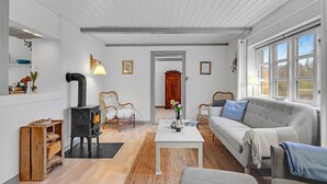 Una sala de estar con chimenea, un sofá, una mesa de centro y vistas al exterior a través de amplios ventanales.