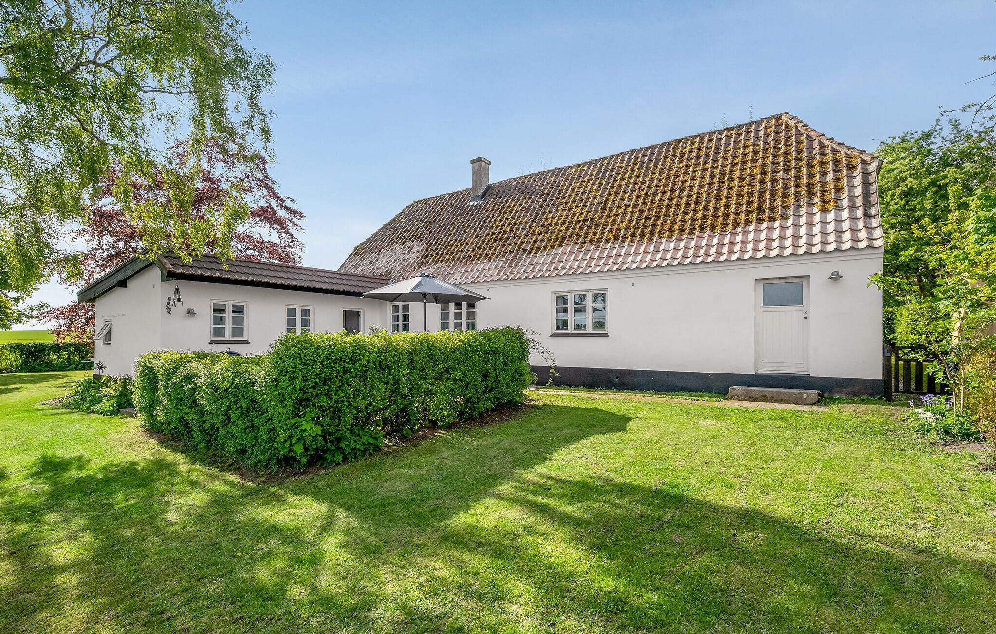 Ein zweistöckiges Haus mit Ziegeldach, einer kleinen angebauten Garage und einem gepflegten Rasen.