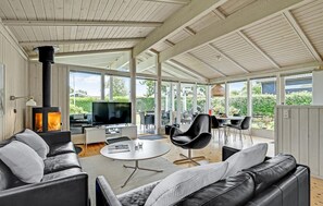 A modern living room with a fireplace, a TV, and a dining area with outdoor views. - Stunning home in Malling with sauna (Malling)