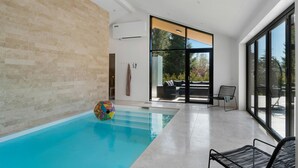 Piscina interior com ampla vista para o exterior através de grandes janelas.