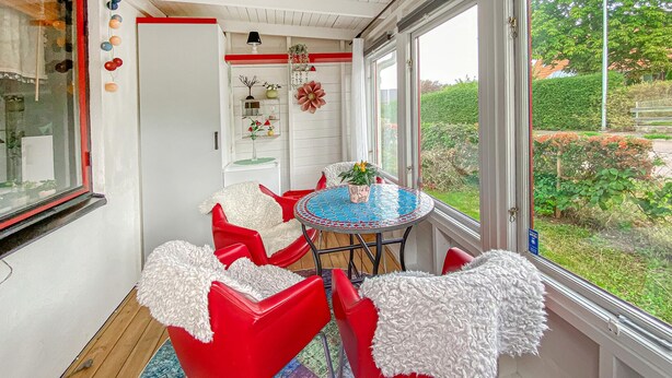A room with a red chair, a round table, and a view of greenery outside. - Lovely apartment in Borgholm with WiFi (Borgholm)