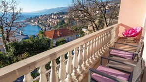 A balcony with a view of a coastal town, a chair, and a table. - Beach front apartment in Opatija with WiFi (Opatija)