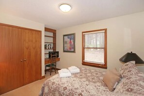 A bedroom with a bed, a desk with a chair, a wardrobe, and a window with blinds. - Cozy, sprawling lakefront house on cove for family fun and entertaining! (Mooresville)