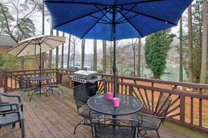 A wooden deck with outdoor furniture, including tables and chairs, and a barbecue grill. - Cozy, sprawling lakefront house on cove for family fun and entertaining! (Mooresville)
