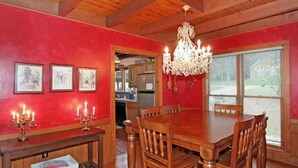 Une salle à manger avec une table et des chaises en bois, un lustre et des tableaux encadrés accrochés au mur.