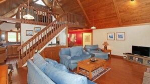 Un vaste salon doté d’un escalier en bois, d’un coin repas et d’une cuisine.