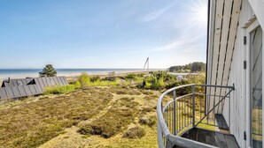 En fastighet vid kusten med en balkong som vetter mot en strand, en gräsyta och fri utsikt över havet.