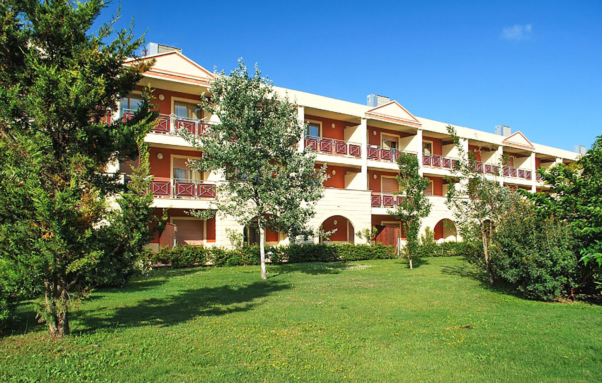 Un hôtel à plusieurs étages doté d’une cour intérieure, de balcons et d’une pelouse bien entretenue.