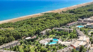 A resort with multiple swimming pools, lush greenery, and a beach in the background.
