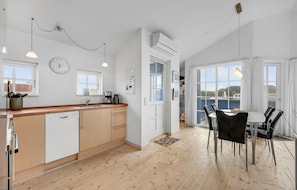 A modern kitchen with a dishwasher, a coffee maker, and a window. There is a dining area with chairs and a table. - Amazing home in Hvide Sande with WiFi (Hvide Sande)