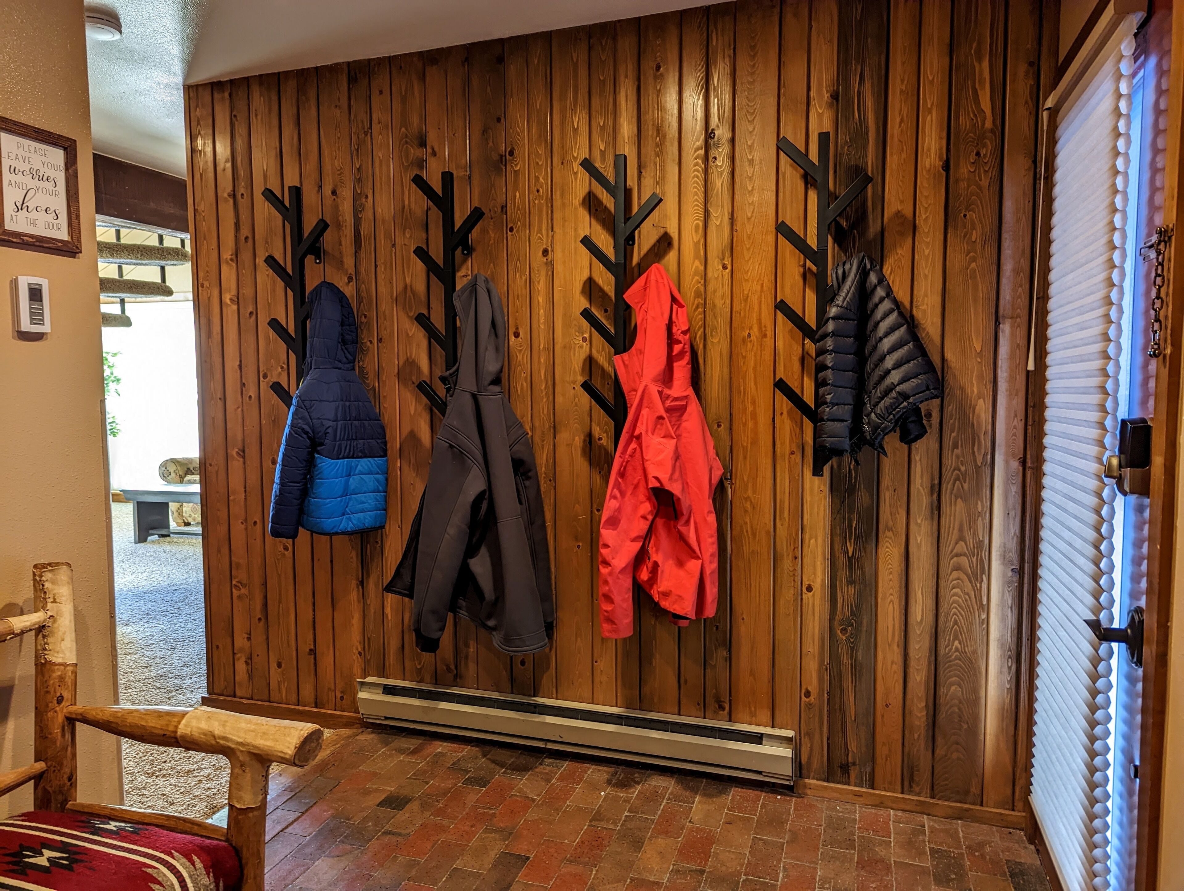 A wooden wall with coat hooks holding various jackets.