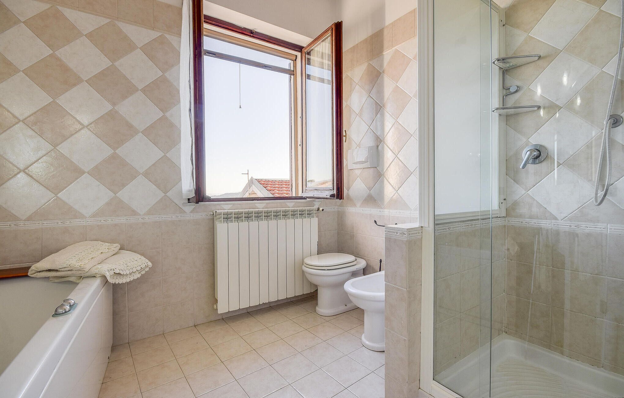 A bathroom with a bathtub, toilet, and glass-enclosed shower.