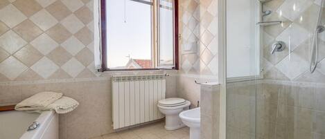 A bathroom with a bathtub, toilet, and glass-enclosed shower.