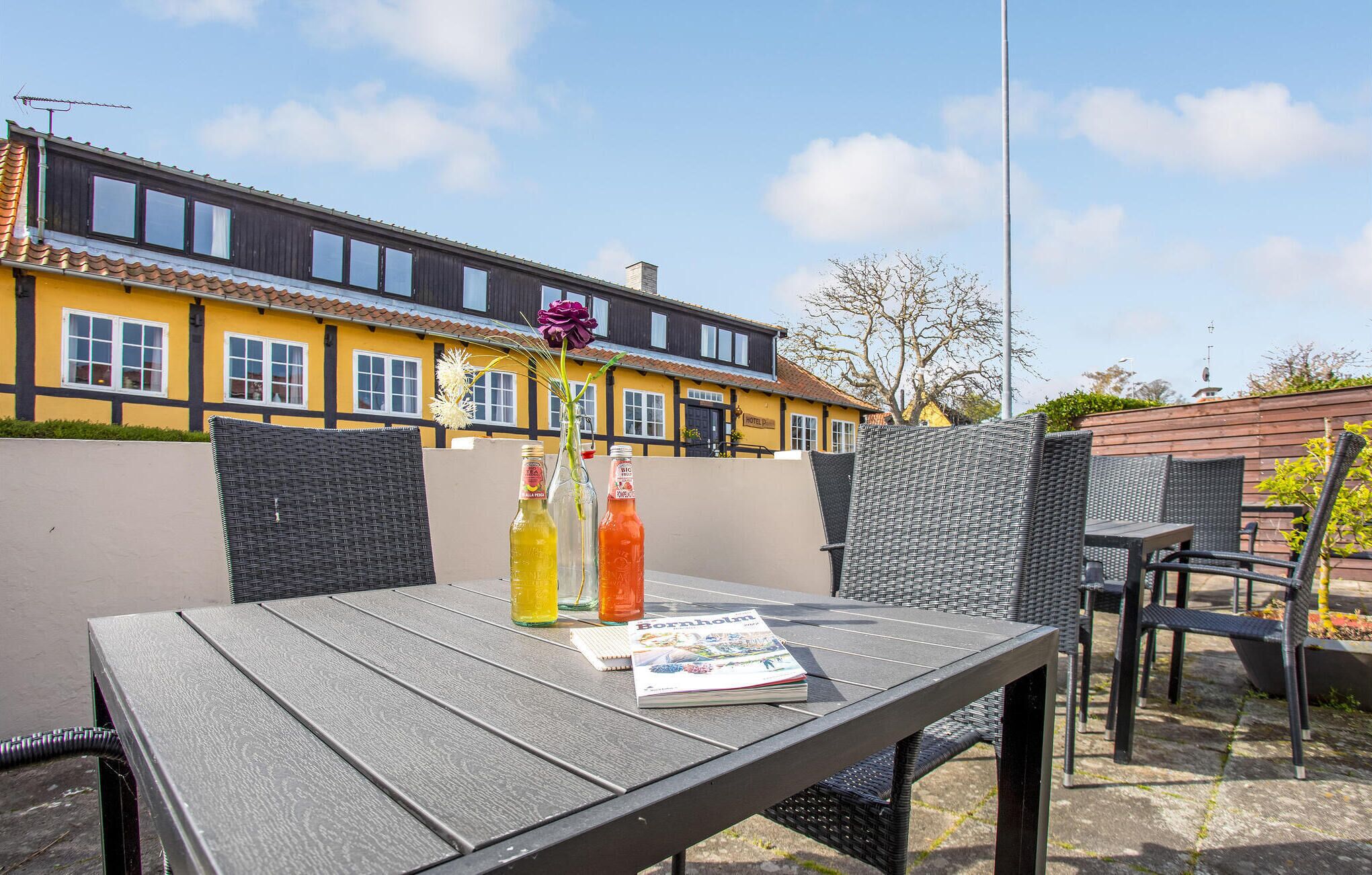 Une terrasse extérieure avec une table, des chaises en osier et un magazine.