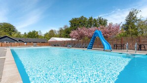 A swimming pool with a blue slide, lounge chairs, and a wooden fence. - Stunning apartment in Hasle (Hasle)
