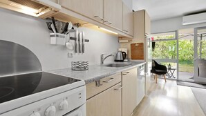 A modern kitchen with a built-in stove, stainless steel sink, and wooden cabinets. - Stunning apartment in Hasle (Hasle)