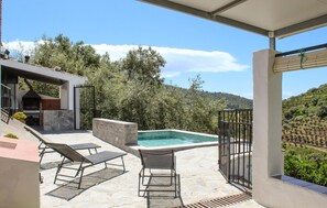 En tagterrasse med swimmingpool, liggestole og grillområde.