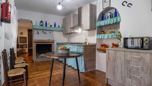 A kitchen with a brick fireplace, wooden cabinets, a dining table with chairs, and a microwave. - Pet friendly home in Sayalonga (Sayalonga)