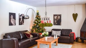 Een woonkamer met een kerstboom, leren banken, een bijzettafeltje en wanddecoratie.