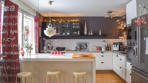 Een moderne keuken met witte kasten, een centraal eiland met krukken, een ingebouwde oven en een koelkast.